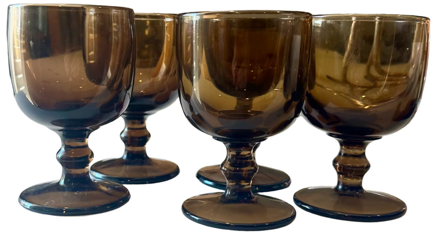 Set of four dark glass goblets on a white surface